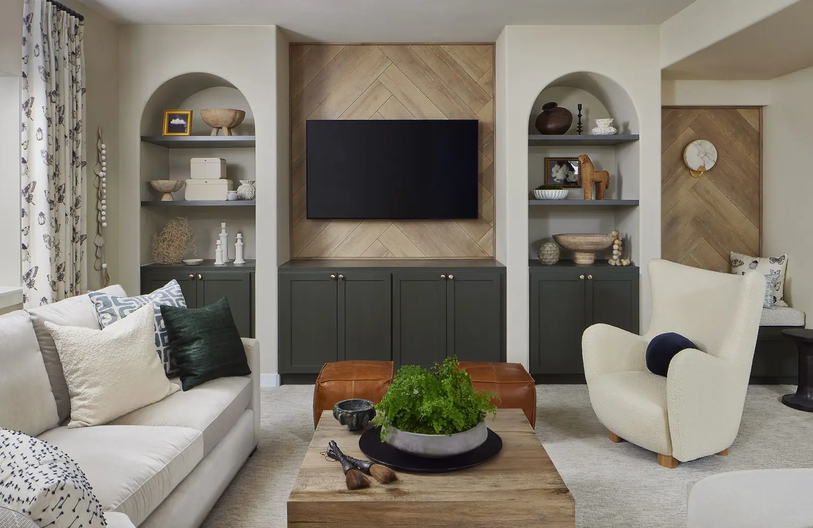 Living room with herringbone media wall and arched built-in shelving